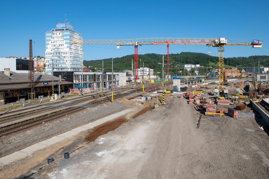 Vlevo betonový základ pro hranu nástupiště, v pozadí hrubá stavba dopravního terminálu - Vsetín (3.6. 2023)